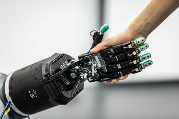 Ein Mensch reicht einer Roboterhand die Hand