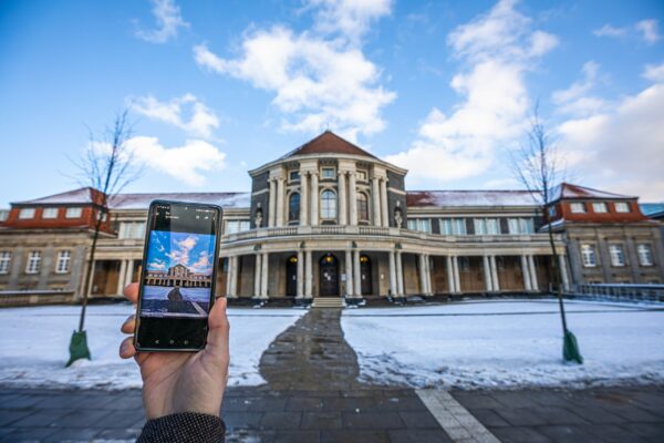 Die Uni Hamburg im Winter mit einem Smartphone im Vordergrund