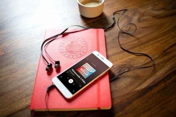 Ein Tisch, auf welchem ein Notizbuch, ein Smartphone und eine Kaffeetasse liegen.