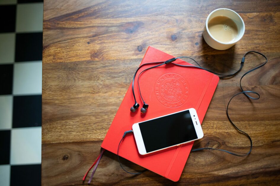 Ein Tisch, auf dem Notizbuch, eine Kaffeetasse und ein Smartphone liegen.