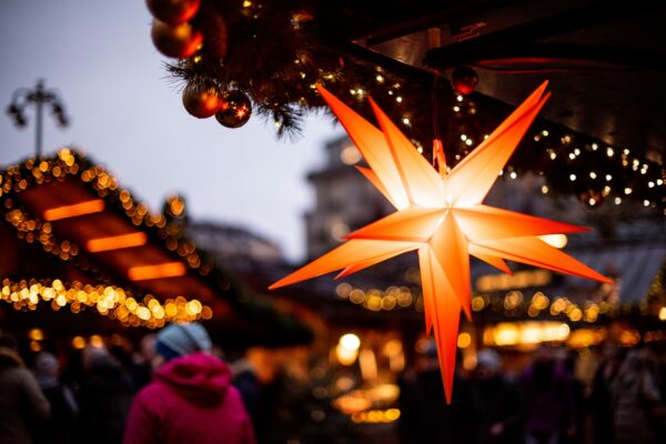 Ein Bild, welches den Weihnachtsmarkt vor dem Hamburger Rathaus zeigt. Ein leuchtender weihnachtlicher Stern ist dabei im Fokus.