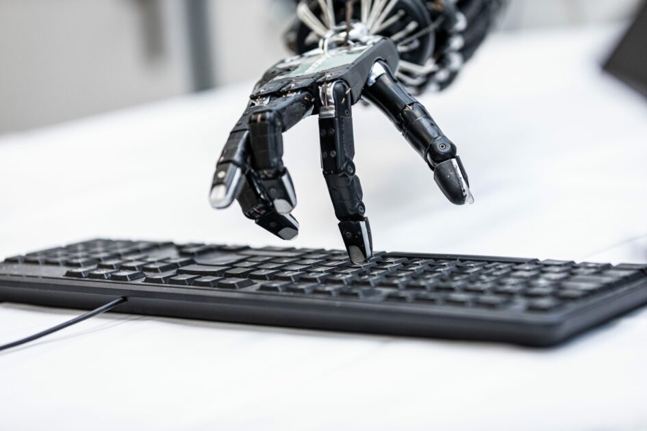 Eine Roboterhand, die mit ihren Fingern auf einer Tastatur tippt.